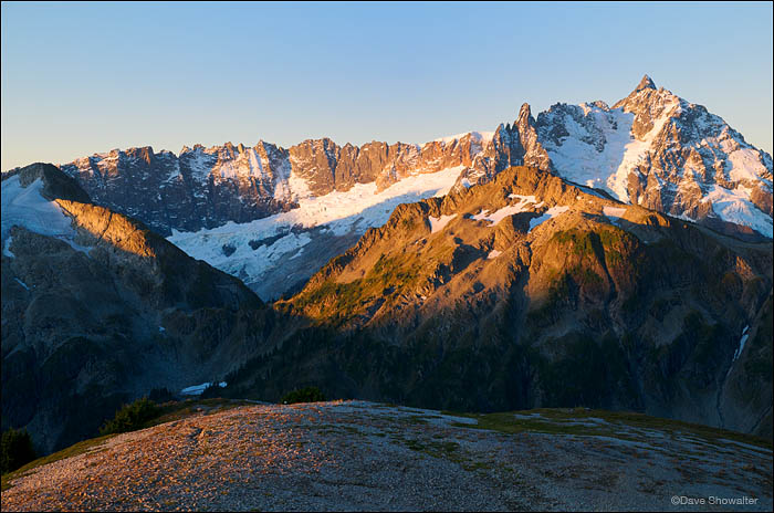 Warm sunrise light highlights the rugged terrain of Shuksan Peak and Jagged Ridge from Hannegan Peak. North Cascades National...
